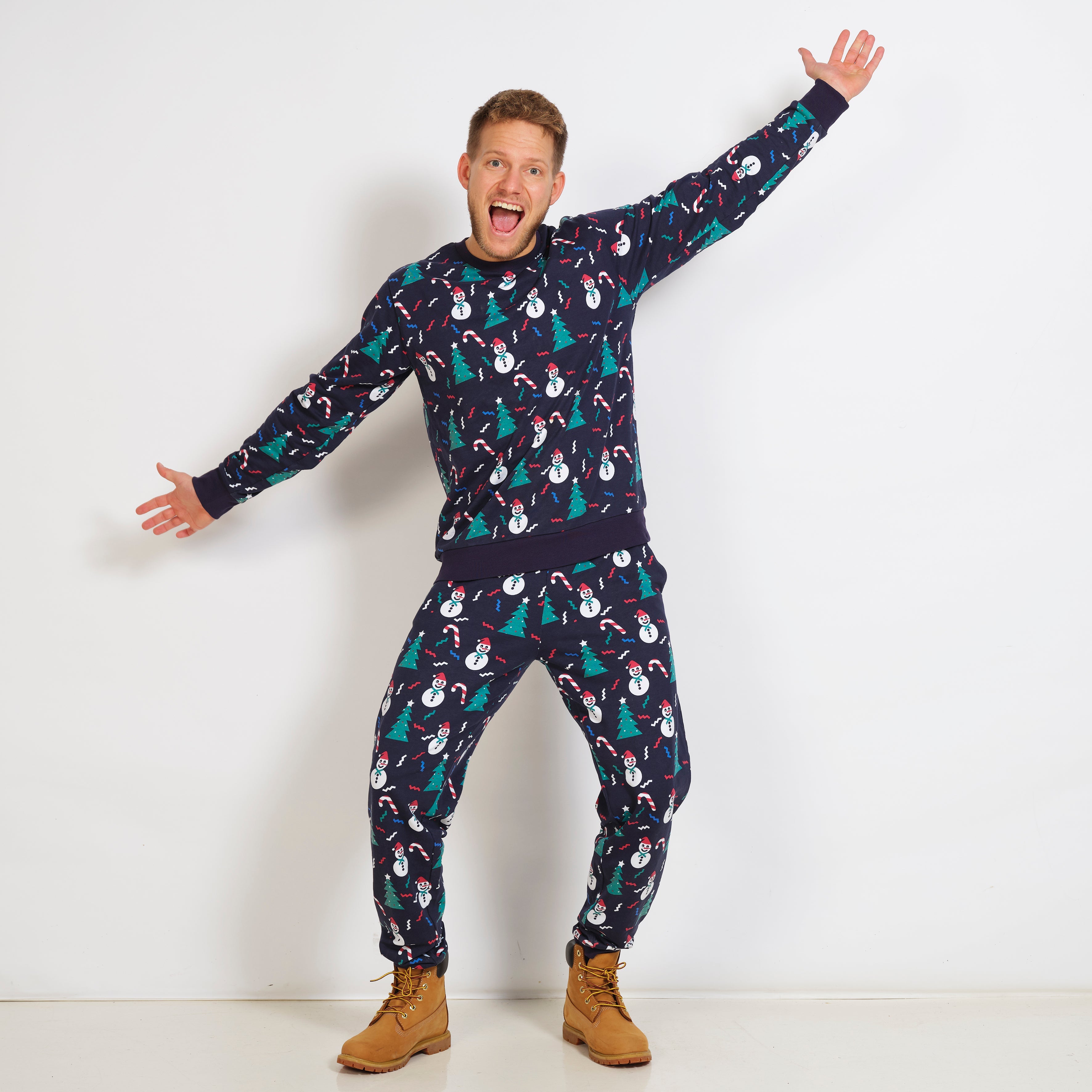 En mann i blå julepyjamas med juletrær på.